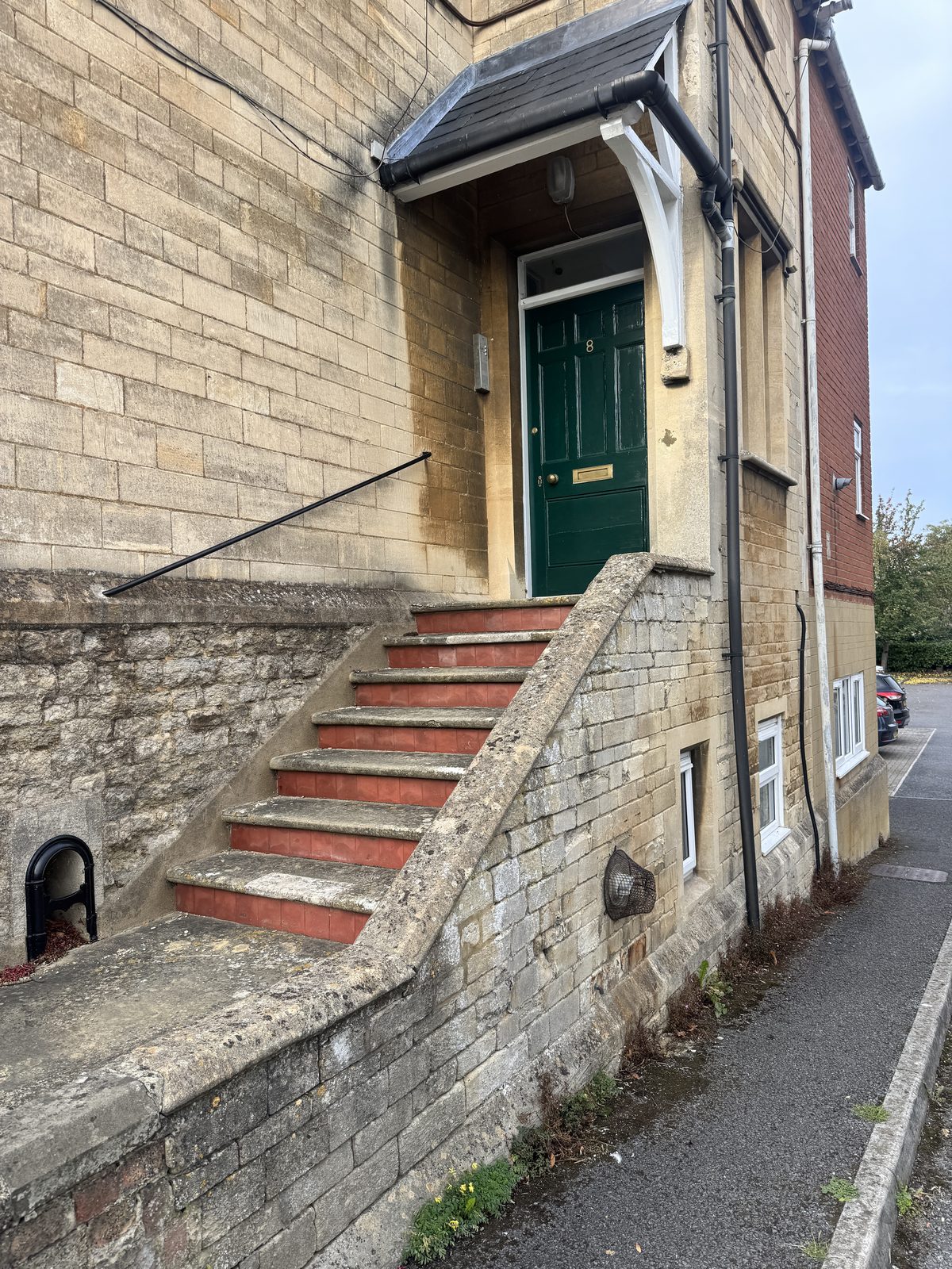 The Loft's own front door, a green painted door reached by stone steps with red tiled risers, in a Cotswold stone building